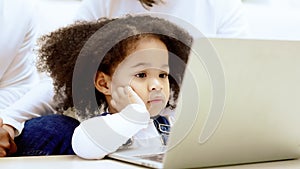 Happy african family parents and little children enjoy using computer laptop together sit on sofa