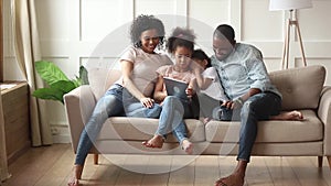Happy african family parents and little children using digital tablet