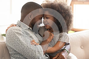 Happy african father and cute child daughter bonding embracing laughing