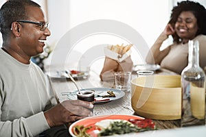 Happy african father drinking yerba mate during lunch at home - Main focus on man face