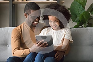 Happy african father and kid daughter using digital tablet