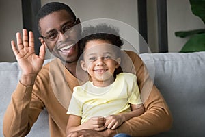 Happy african father and kid son waving hands recording vlog