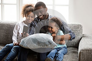 Happy african father taking selfie with cute kids on smartphone