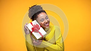 Happy african female holding present box with red bow, birthday gift surprise