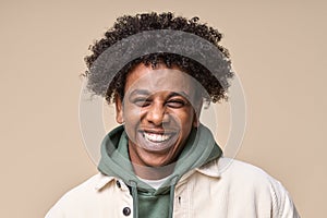 Happy African gen z guy laughing isolated on beige background, closeup portrait.