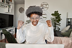 Happy African gen z student getting good news celebrating looking at laptop.