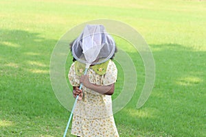 Happy African girl with black curly hair plays fun with scoop-net for catching insect bug and butterfly in green garden. Child