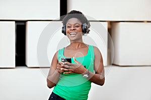 Happy African girl listens to music with wireless headphones on her mobile phone and dances. The girl is enjoying the