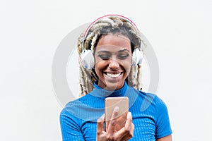 Happy african girl watching videos and listening music with mobile phone app - Young person having fun with new technology trends