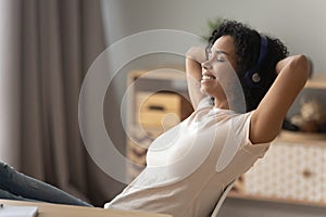 Happy african girl wearing headphones relaxing listening to music