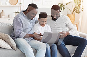 Happy African Granddad, Father And Preteen Son Using Laptop At Home Together