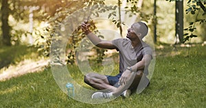 Happy african guy taking selfie on mobile phone in park