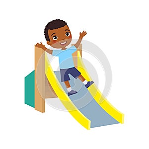 Happy African little  boy slides off a children`s slide. Joyful dark skin child, summer vacation