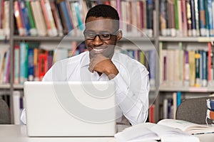 Happy African Male Student With Laptop In Library