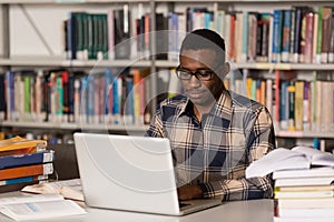 Happy African Male Student With Laptop In Library