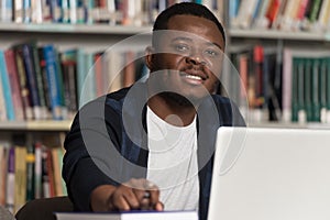 Happy African Male Student With Laptop In Library