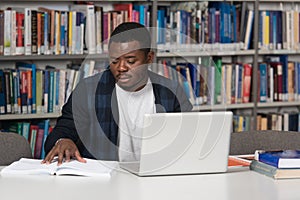 Happy African Male Student With Laptop In Library