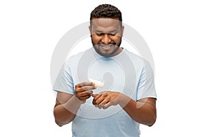 Happy african man applying moisturizer to his hand