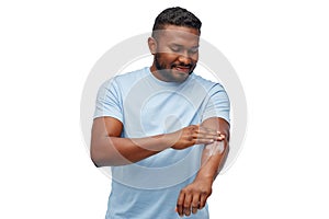 Happy african man applying moisturizer to his hand