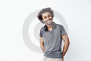 Happy african man with headphones on his nech listening to streaming music smiling looking at camera over white
