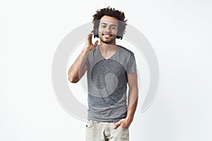 Happy african man in headphones smiling looking at camera over white background.