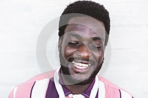 Happy african man laughing in front of camera - Portrait of young black person having fun outdoor - Focus on face