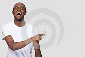 Happy african man laughing pointing finger aside at copy space photo