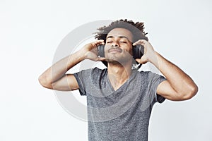 Happy african man smiling listening to music in headphones. Closed eyes.