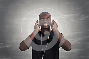 Happy african man smiling listening to music in headphones. Grey background.