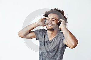 Happy african man smiling listening to music in headphones. White background.