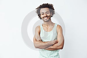 Happy african man smiling posing with crossed arms over white background. Copy space.