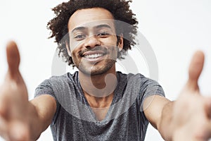 Happy african man smiling stretching hands to camera over white background.