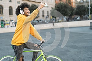 Happy African man taking selfie with mobile smartphone outdoor - Young guy having fun riding with bike in the city
