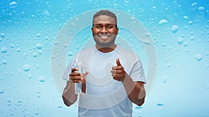 Happy african man with water in glass bottle