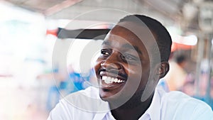 Happy african man wearing white shirt smiling openly in community area. Positive black ethnic man with healthy white teeth,