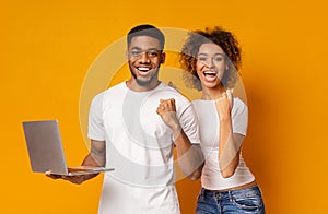 Happy african man and woman enjoying lottery win with laptop