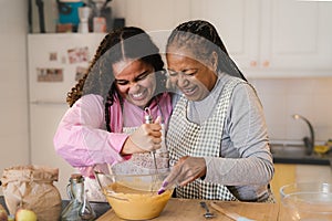 Happy African mother and daughter having fun preparing a homemade dessert
