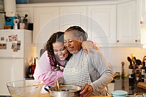 Happy African mother and daughter preparing a dessert