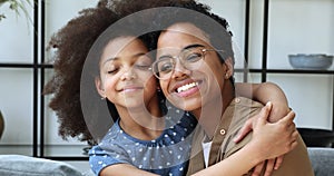 Happy African preteen daughter cuddle beloved mom with closed eyes