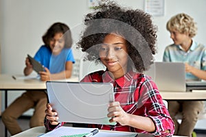 Happy African school girl using digital tablet computer at class in classroom.