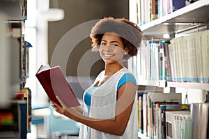 Happy african student girl reading book at library