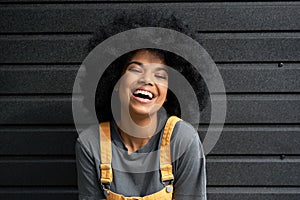 Happy African teen hipster girl with Afro hair laughing at camera, headshot.