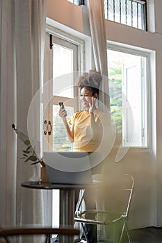 Happy african woman holding smart phone watching social media video content. Smiling young black teen gen z girl using