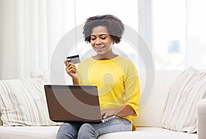 Happy african woman with laptop and credit card