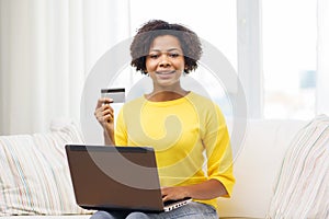 Happy african woman with laptop and credit card