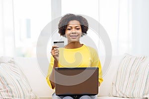 Happy african woman with laptop and credit card