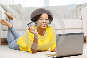 Happy african woman with laptop and credit card