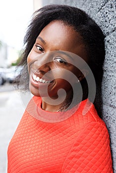 Happy african woman leaning against wall