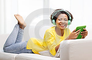 Happy african woman with tablet pc and headphones