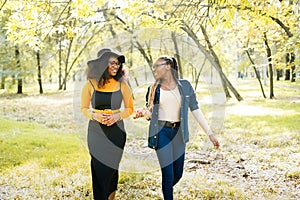 Happy african women friends walking outdoors in the park